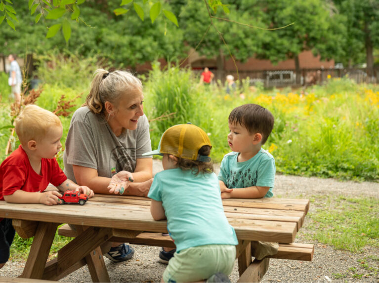 Teacher with students outdoors at picnic table