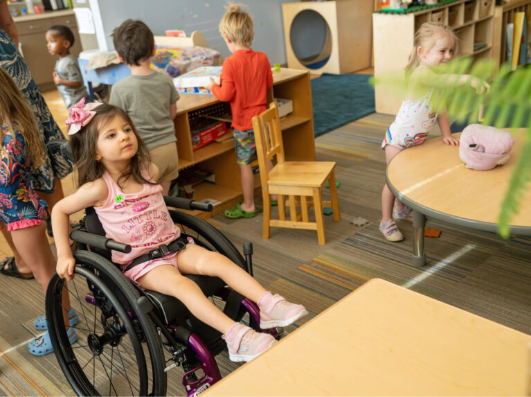 Preschool girl in wheelchair at desk