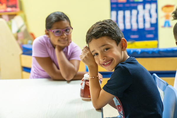 Preschool boy smiling at camera with girl in background
