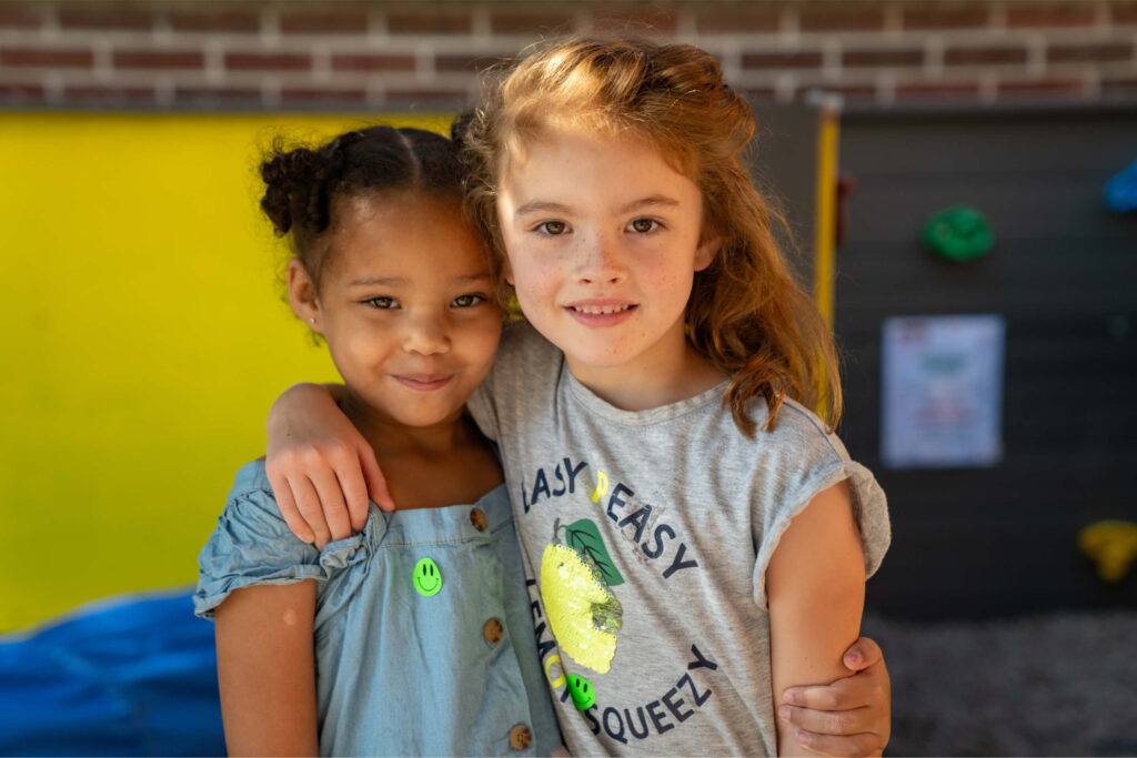Two preschool girls with arms over one another's shoulders