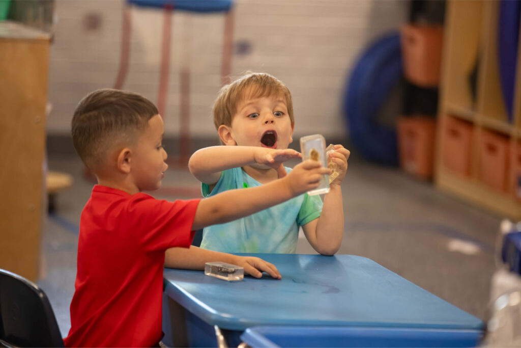 Two young preschool aged boys in a classroom together.