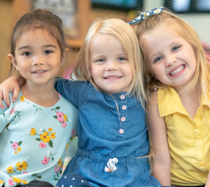 Três meninas se abraçando e sorrindo