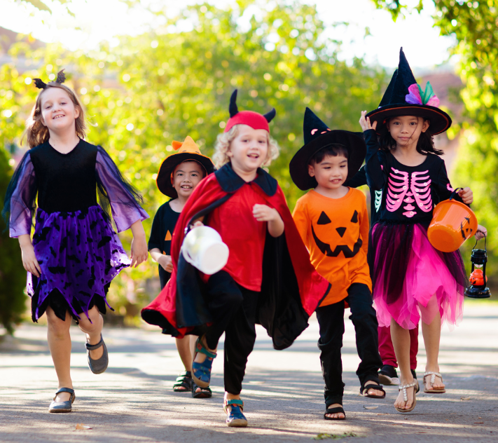 Kinder in Halloweenkostümen rennen die Straße entlang