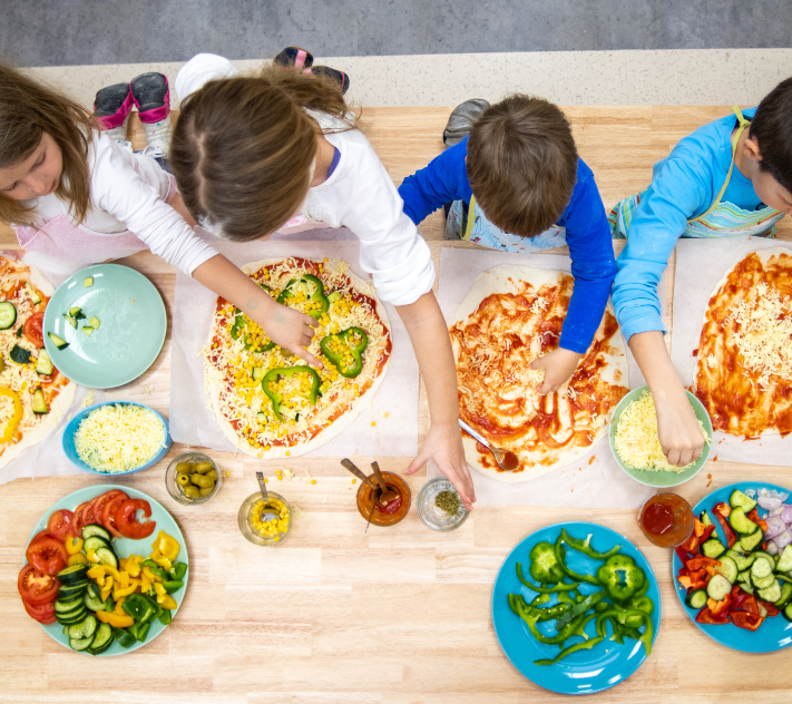 Vier kleine Kinder machen Pizza