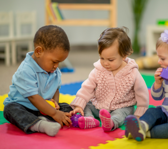 幼い子供二人が床で積み木で遊んでいる。.