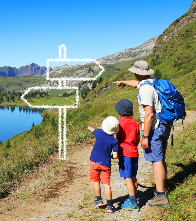 Young boys and father on a hiking trail by a lake pointing to a mountain