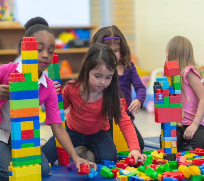 Young children playing with colorful blocks on the floor.